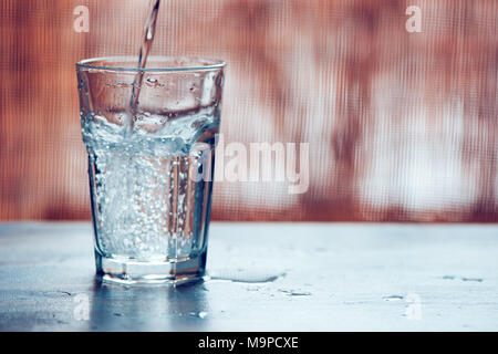 Verser l'eau gazeuse fraîche en verre sur la table, selective focus Banque D'Images