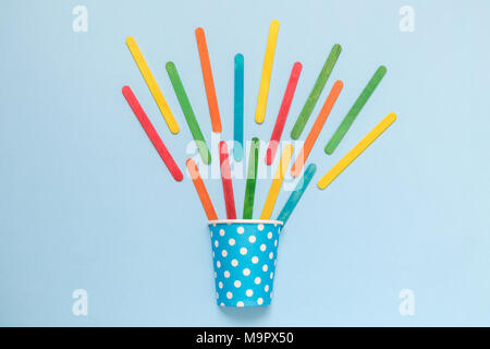 Mise à plat de papier tasse design à pois colorés et des bâtonnets de glace sur fond bleu pastel un minimum de concept créatif. Banque D'Images