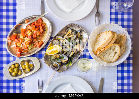 Table couverts avec les palourdes délicieux servi sur de l'argenterie, vin blanc, pain, salade de tomates et olives d'au-dessus, Portugal Banque D'Images