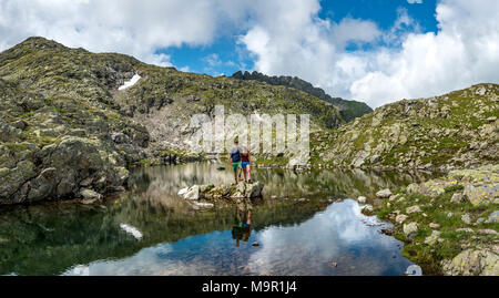 Deux randonneurs se dresse sur une pierre dans un petit lac, Klafferkessel, Schladminger Tauern Schladminger, Höhenweg, Schladming, Styrie Banque D'Images