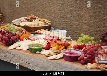 Un lumineux colorés & sélection de fruits, fromages, charcuteries, trempettes et craquelins réparties sur une belle planche de bois. Banque D'Images