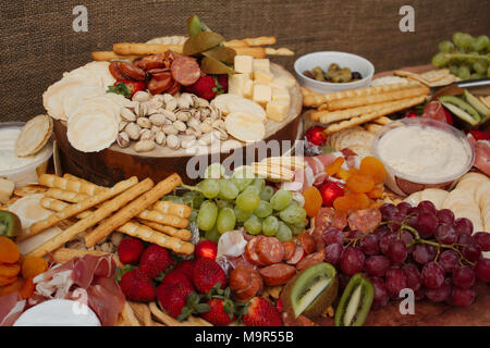 Un lumineux colorés & sélection de fruits, fromages, charcuteries, trempettes et craquelins réparties sur une belle planche de bois. Banque D'Images