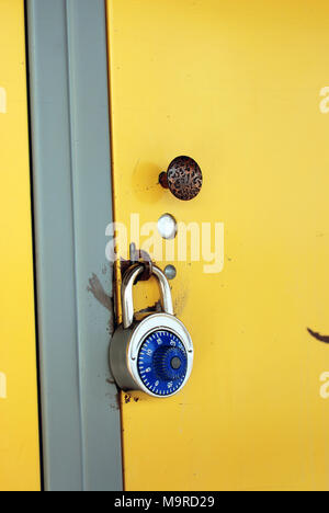 Casier de l'école jaune avec serrure à combinaison bleu - la porte d'un casier jaune dans le couloir d'une école, verrouillé par une serrure à combinaison d'acier inoxydable. Banque D'Images