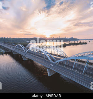 Automobile et le pont de chemin de fer à Kiev, la capitale de l'Ukraine. Bridge au coucher du soleil à travers le fleuve Dniepr. Pont de Kiev dans le contexte d'une beaut Banque D'Images