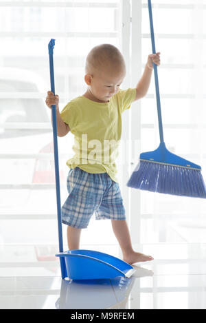 Bébé garçon asiatique étage panoramique avec un balai. Jeune enfant faire travaux domestiques à la maison. Banque D'Images