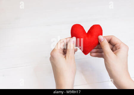 Femme hands holding heart figure faite de tissu rouge Banque D'Images