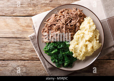 Botswana cuisine : seswaa ragoût de boeuf avec pap de porridge et de l'épinard close-up sur une plaque sur une table horizontale. haut Vue de dessus Banque D'Images