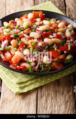 Piyaz turc avec salade de haricots, tomates, oignons, poivrons et coriandre close-up sur une plaque verticale. Banque D'Images