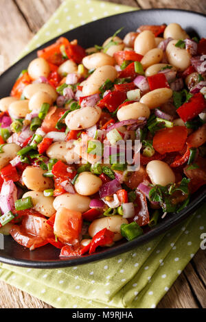 Salade de haricots turc Piyaz avec tomates, oignons, poivrons et coriandre close-up sur une plaque verticale. Banque D'Images