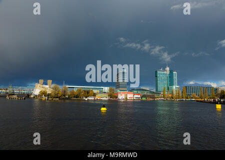 Nuages sombres sur les bâtiments de bureaux à l'Oosterdok à Amsterdam aux Pays-Bas. Banque D'Images