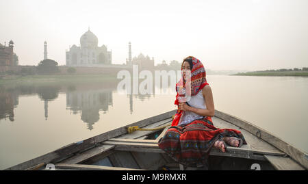Une femme regardant le coucher du soleil sur le Taj Mahal à partir d'un bateau en bois. Banque D'Images