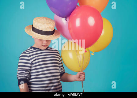 Garçon attentionné avec des ballons sur fond bleu Banque D'Images