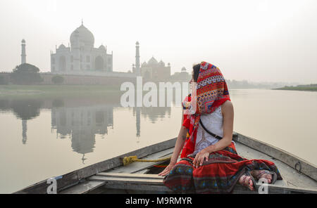 Une femme asiatique regardant le coucher du soleil sur le Taj Mahal à partir d'un bateau en bois. Banque D'Images