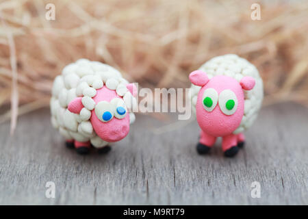 Monde de pâte à modeler - peu des moutons blancs avec des yeux bleu et vert sur une ferme sur fond de foin, selective focus Banque D'Images