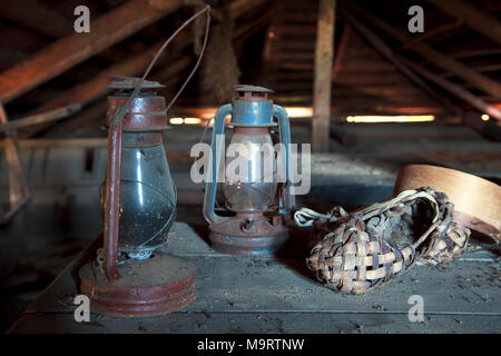 Fédération vintage articles ménagers. Stilllife. Vieille bast chaussures, la grille en bois et une lampe au kérosène dans un grenier poussiéreux dans la maison de campagne. Focus sélectif. Banque D'Images