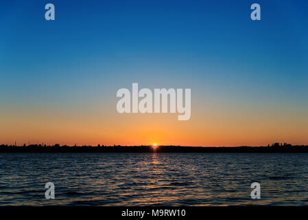 L'eau sombre dans la rivière et le lever du soleil sur elle. premier rayons de soleil sur la rivière dans la région de Clear Sky Banque D'Images