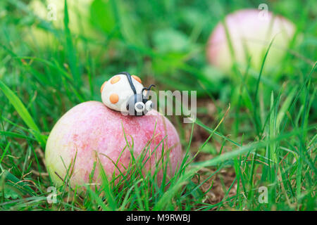 Monde - Pâte à modeler maison peu coccinelle blanche assise sur un tombé apple, selective focus on head, de l'espace pour le texte Banque D'Images