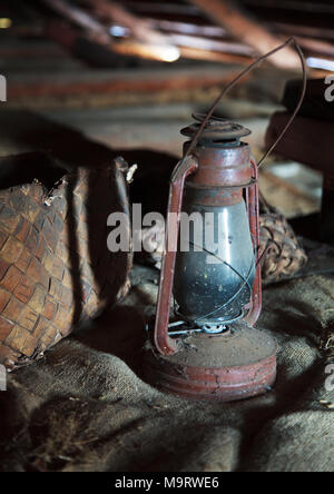 Fédération vintage articles ménagers. Stilllife. Vieille bast chaussures et une lampe au kérosène sur un morceau de sac dans un grenier poussiéreux dans la maison de campagne. Selective Banque D'Images