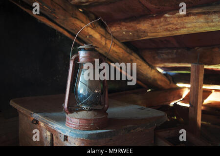 Rare lampe à kérosène poussiéreux se dresse sur le vieux tronc sous le plafond dans un vieux grenier rustique, selective focus, de l'espace pour le texte Banque D'Images