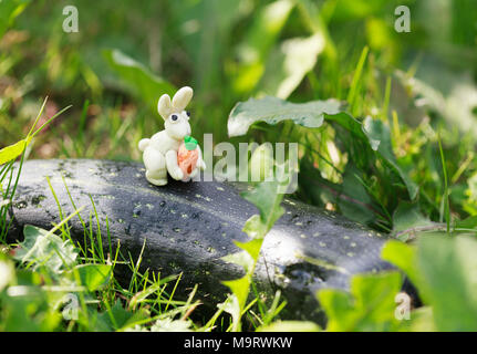 Monde - Pâte à modeler maison petit lapin blanc à la carotte assis sur une courgette, selective focus Banque D'Images