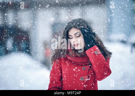 Portrait d'hiver jeune belle brunette woman wearing snood tricoté veste rouge et couvertes de neige. Hiver Neige Neige beauty fashion concept. Banque D'Images