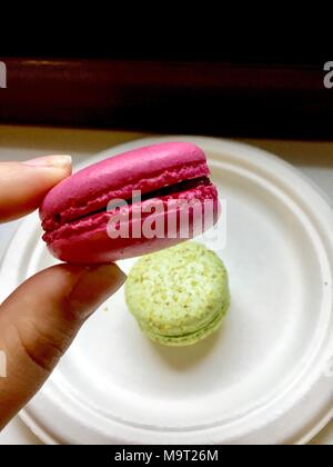 Différents types de macarons en mouvement qui tombe sur un fond de bois blanc. Banque D'Images