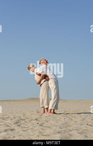 Senior couple in love marche pieds nus dans le sable à l'été Banque D'Images