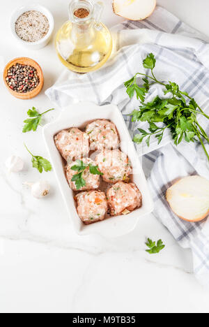 Des matières premières ou de poulet boulettes de dinde dans le plat de cuisson sur fond de marbre blanc. L'espace de copie. Vue de dessus Banque D'Images