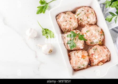 Des matières premières ou de poulet boulettes de dinde dans le plat de cuisson sur fond de marbre blanc. L'espace de copie. Vue de dessus Banque D'Images