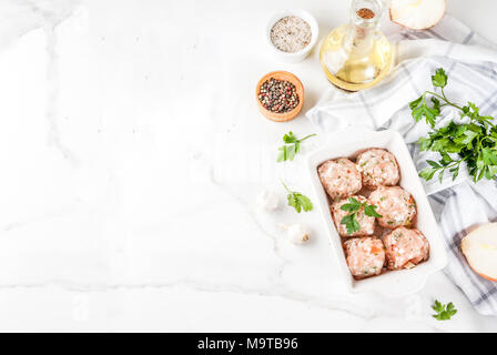 Des matières premières ou de poulet boulettes de dinde dans le plat de cuisson sur fond de marbre blanc. L'espace de copie. Vue de dessus Banque D'Images