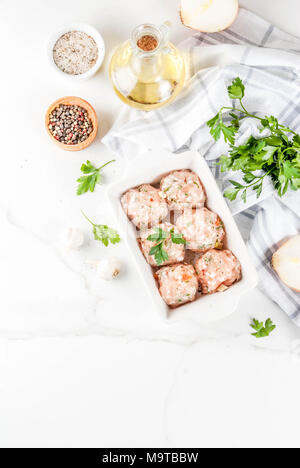 Des matières premières ou de poulet boulettes de dinde dans le plat de cuisson sur fond de marbre blanc. L'espace de copie. Vue de dessus Banque D'Images