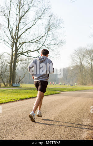 Homme qui court sur un chemin d'asphalte dans l'Amsterdamse Bos. Banque D'Images