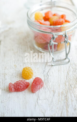 Gummy vitamines dans le bocal en verre blanc sur fond de bois. Bonbons multivitaminés en forme de différentes sortes de fruits. Supplément Nutrition concept. Banque D'Images