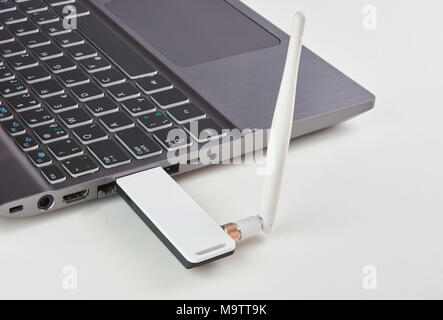 Ordinateur portable avec modem USB Argent branché avec une antenne, sur une table de carte blanche Banque D'Images