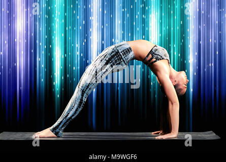 Fit la démonstration d'une femme athlétique pattes droites pose des roues pendant le yoga se cambrant avec pieds et mains sur le tapis dans une petite v Banque D'Images