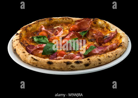 Pizza au prosciutto, tomates cerises et basilic isolé sur fond noir Banque D'Images