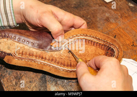 La fixation des fils à coudre d'une chaussure en cuir marron présente le savoir-faire d'un cordonnier à Oegstgeest néerlandais aux Pays-Bas. Banque D'Images