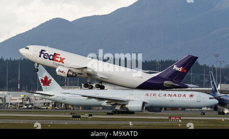 Richmond, Colombie-Britannique, Canada. Mar 27, 2018. FedEx Express un Airbus A300 (N717FD) air cargo freighter décolle de l'Aéroport International de Vancouver. Dans l'arrière-plan un Boeing 777-300ER d'Air Canada le long de la piste de taxis position de décollage. Credit : Bayne Stanley/ZUMA/Alamy Fil Live News Banque D'Images