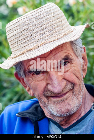 Un portrait d'un beau sourire, un homme âgé dans la région de hat à l'extérieur. Banque D'Images