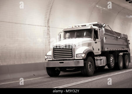 Puissant gros camion benne camion semi compact se déplace sur la route qui traverse un tunnel souterrain avec des murs arrondis Banque D'Images