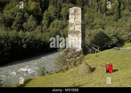 Un couple en costume national géorgien à pied près de l'Ingouri (Rivière Enguri) et la légendaire Tour de l'amour à Kala, Upper Svaneti, Géorgie Banque D'Images