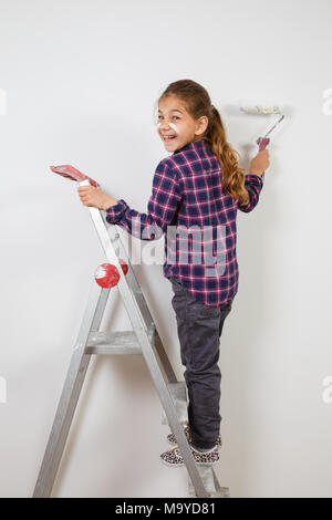 Fille de l'adolescence à l'aide d'un pinceau peintre sur mur blanc dans la chambre. La réparation à la maison Banque D'Images