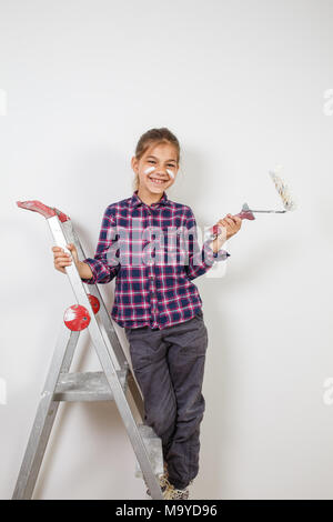 Fille de l'adolescence à l'aide d'un pinceau peintre sur mur blanc dans la chambre. La réparation à la maison Banque D'Images