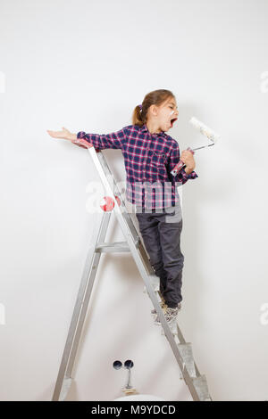 Fille de l'adolescence à l'aide d'un pinceau peintre sur mur blanc dans la chambre. La réparation à la maison Banque D'Images