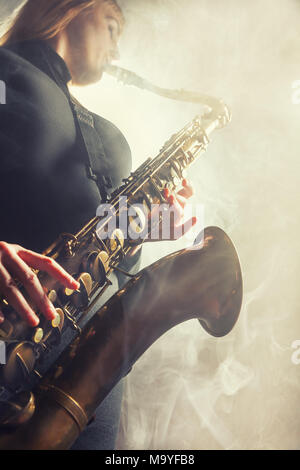 Saxophoniste. Femme avec saxophone sur un fond beige. Le brouillard à l'arrière-plan. Studio shot Banque D'Images