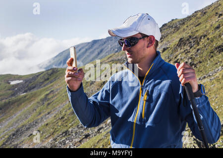 Hipster homme tire une vidéo d'un paysage de montagne avec des nuages sur un téléphone mobile, alors que l'article de fond contre les hauts sommets. L'homme est tak Banque D'Images