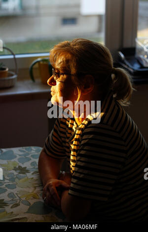 Portrait d'une femme mature à la retraite assis à la table. Banque D'Images