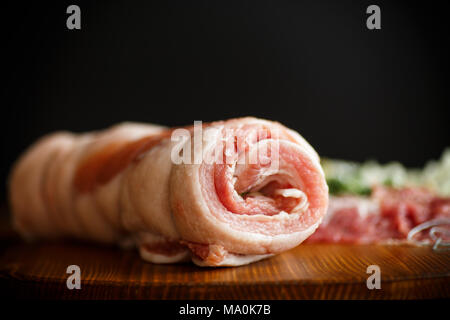 Rouleau de viande avec diverses épices et fines herbes sur une table en bois Banque D'Images