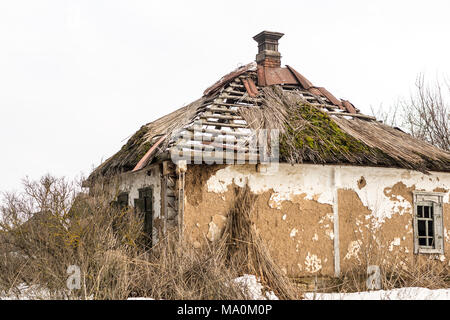 Vieille maison abandonnée. Bâtiment en ruines vieillies avec toit de paille brisée. De fait ofrocks accueil rural, pierre et argile. Banque D'Images