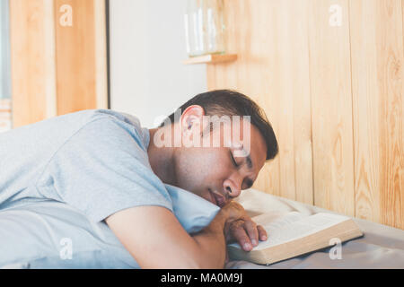 Asian man sleeping après avoir lu le livre sur son lit Banque D'Images